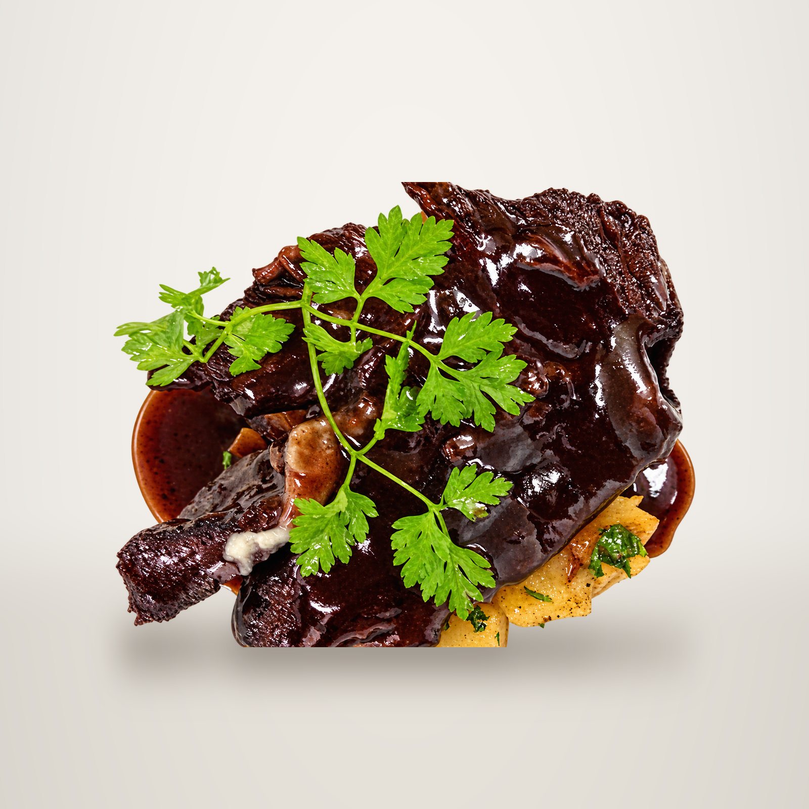 Gros plan sur une pièce de viande braisée brillante, nappée de sauce brune et décorée d'une brindille de cerfeuil, posée sur des pommes de terre dans une assiette blanche.