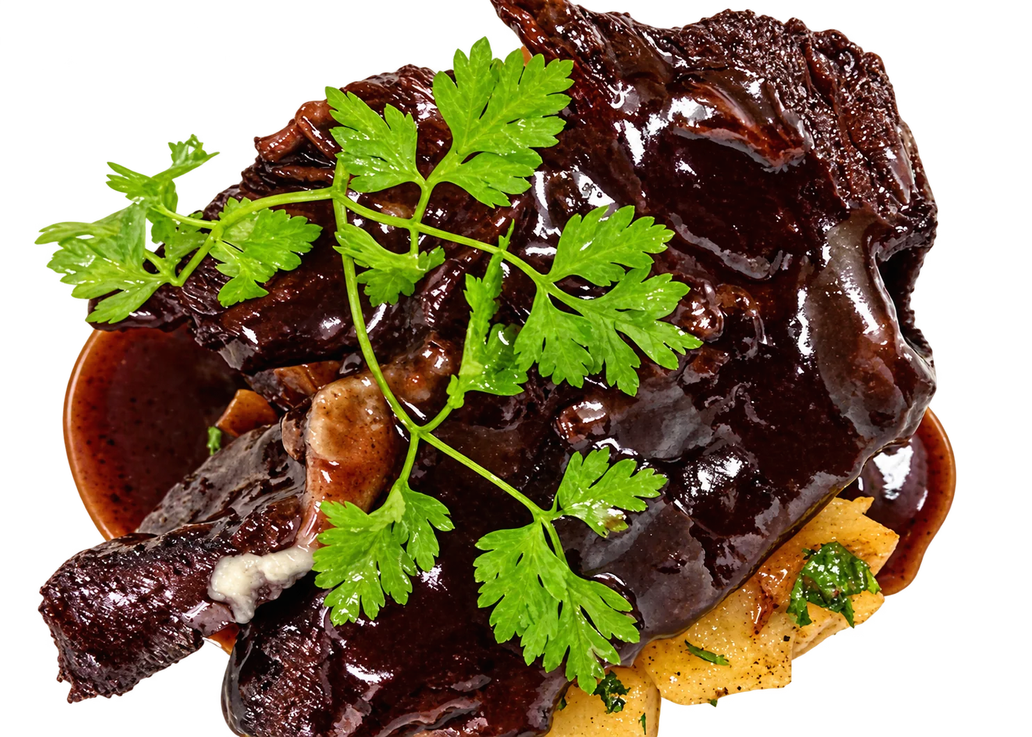 Gros plan sur une pièce de viande braisée brillante, nappée de sauce brune et décorée d'une brindille de cerfeuil, posée sur des pommes de terre dans une assiette blanche.